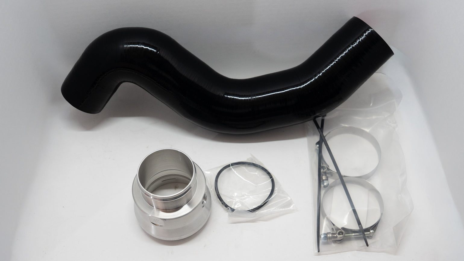 Black automotive silicone tube with ring clamps and other installation components on a white background.