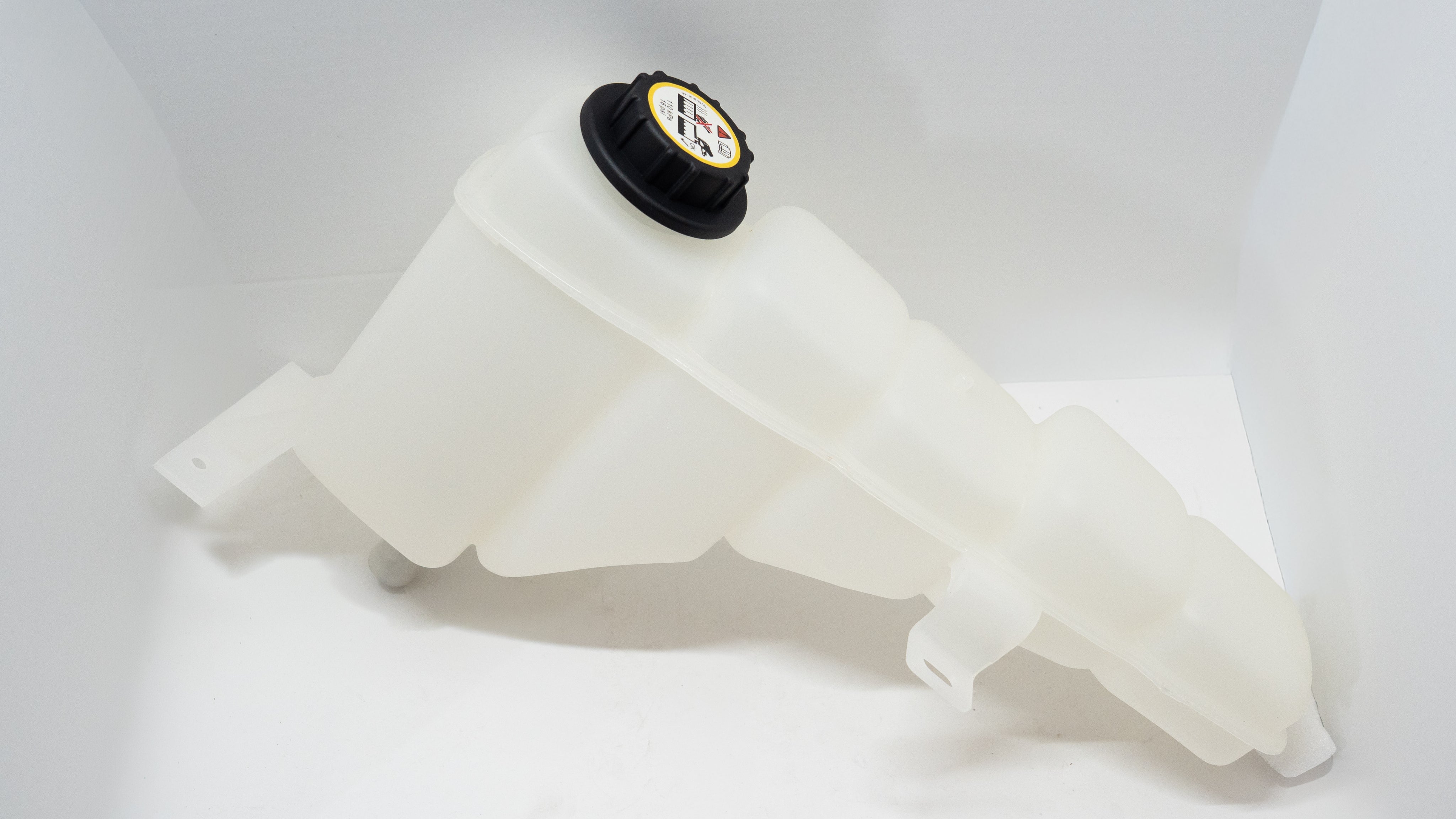 White plastic auto reservoir tank with a black cap on a white background