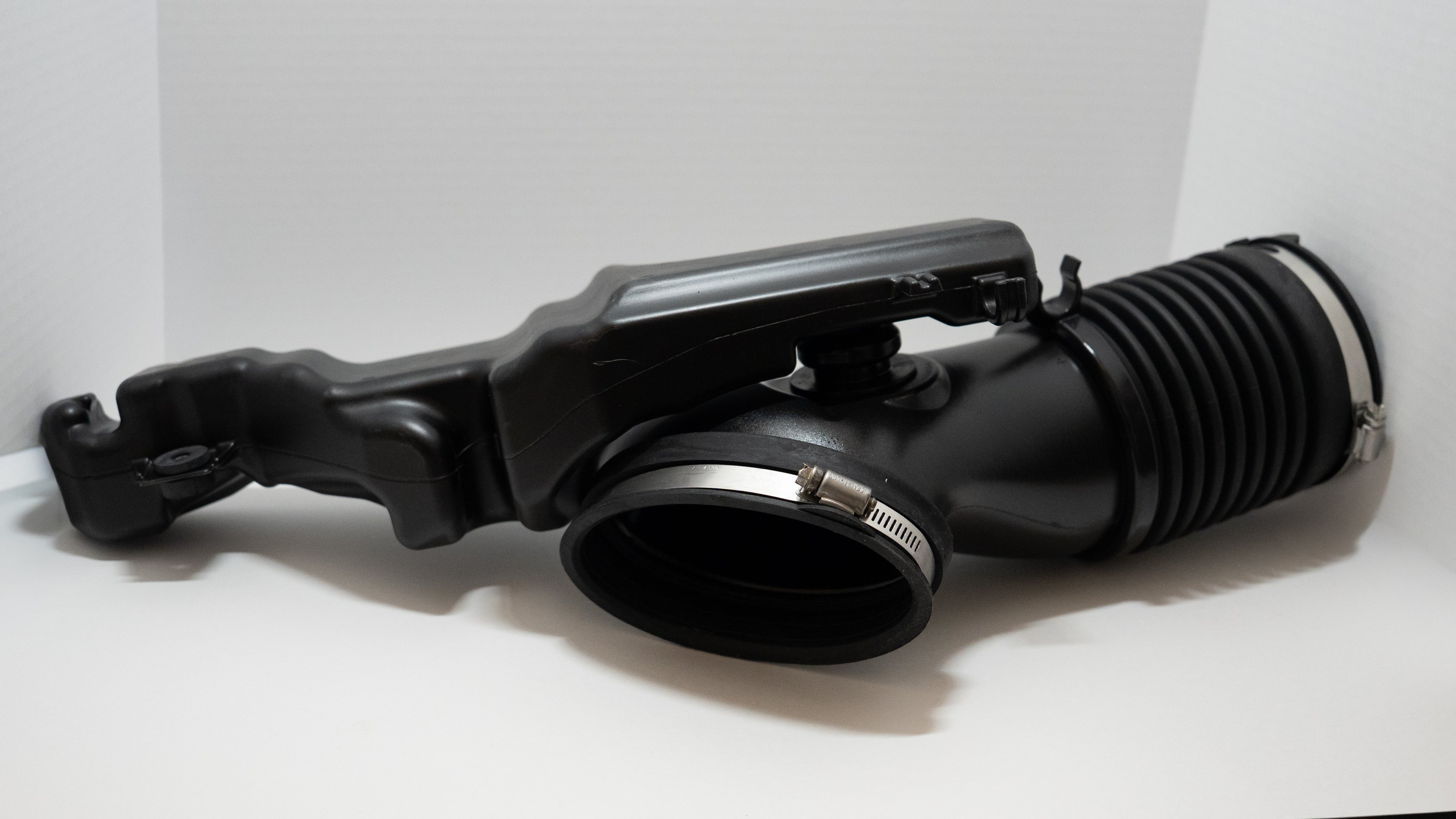 Black automotive air intake system on a white background.