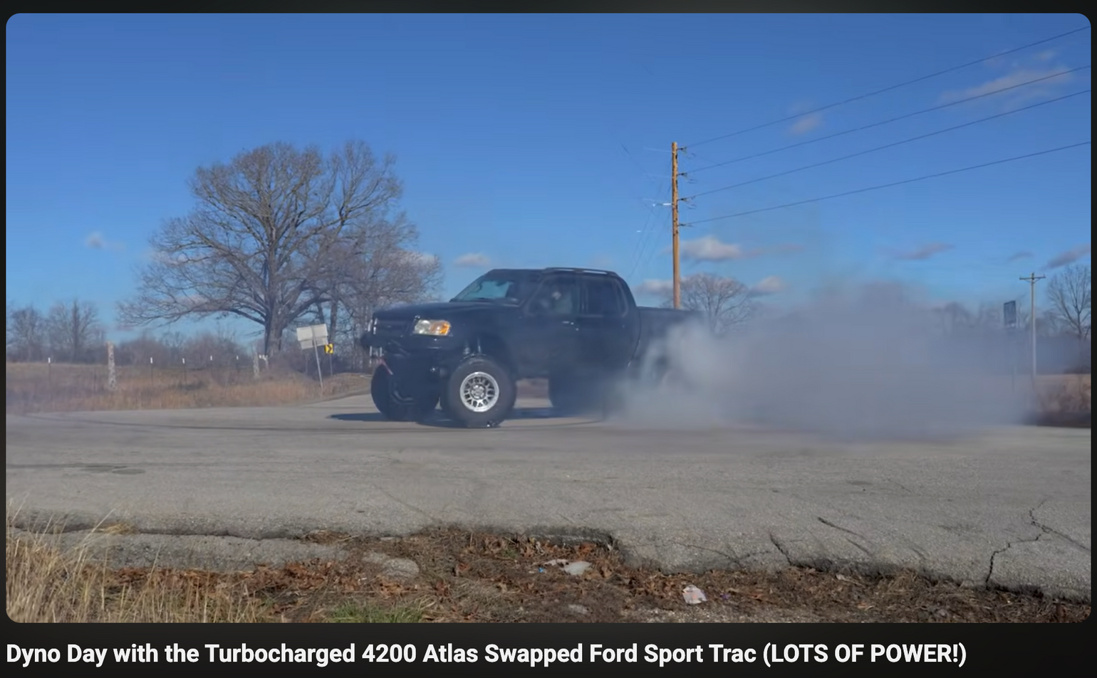 Black truck performing a burnout on a road with text about a turbocharged vehicle.