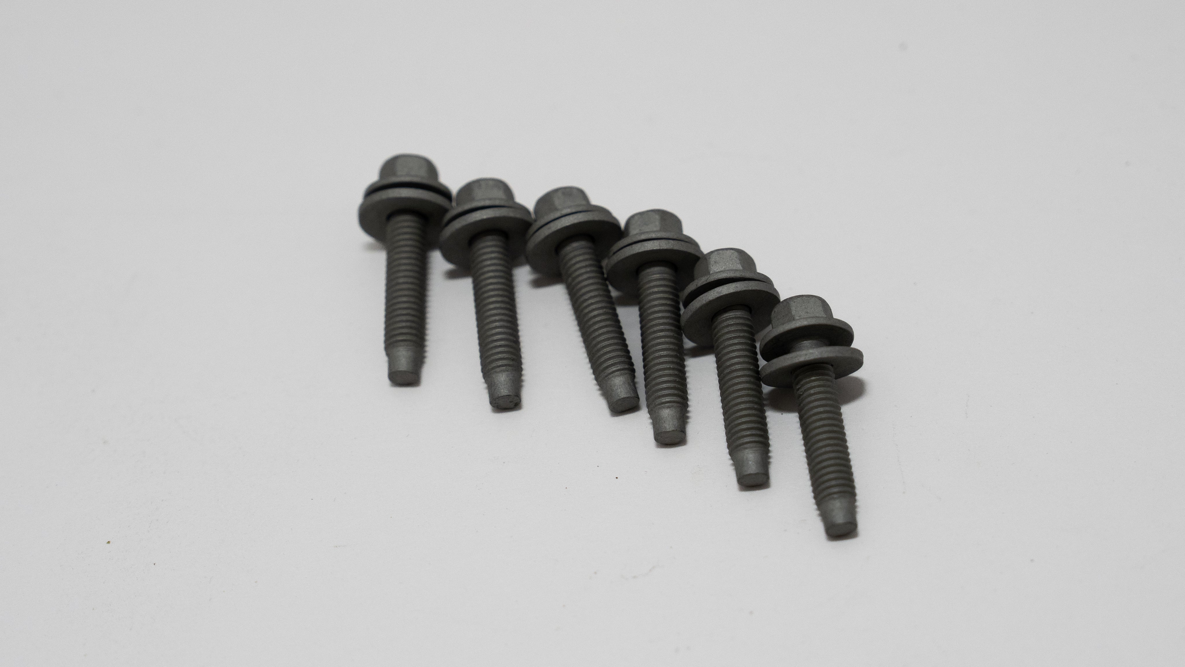 Set of black automotive screws with washer on a gray background.