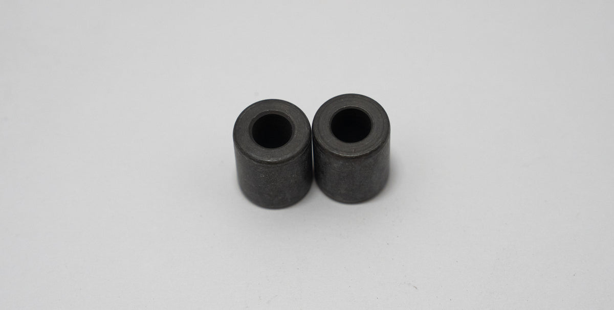 Two black cylindrical automotive spacers on a gray background