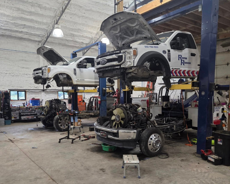 Diesel automotive repair shop with vehicles on lifts and tools scattered around.