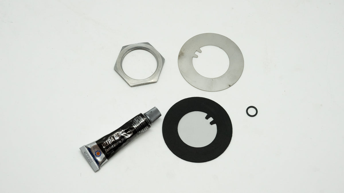 Mechanical repair kit including a tube of grease and metal washers on a white background