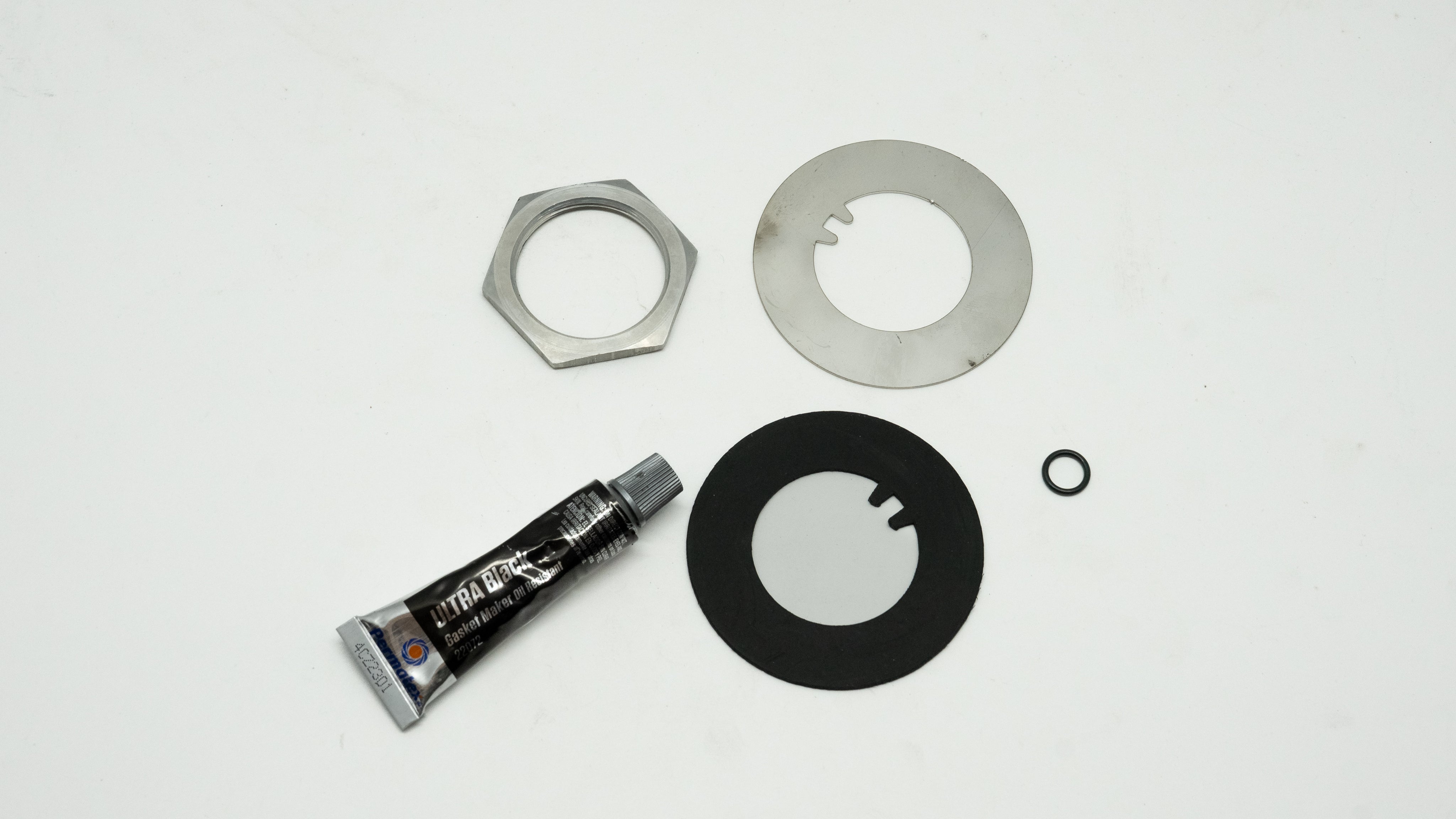 Mechanical repair kit including a tube of grease and metal washers on a white background