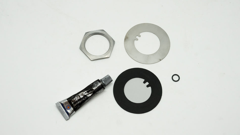 Mechanical repair kit including a tube of grease and metal washers on a white background