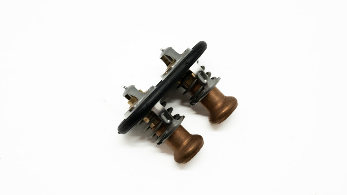 Automotive thermostat with brass knobs on a white background. 