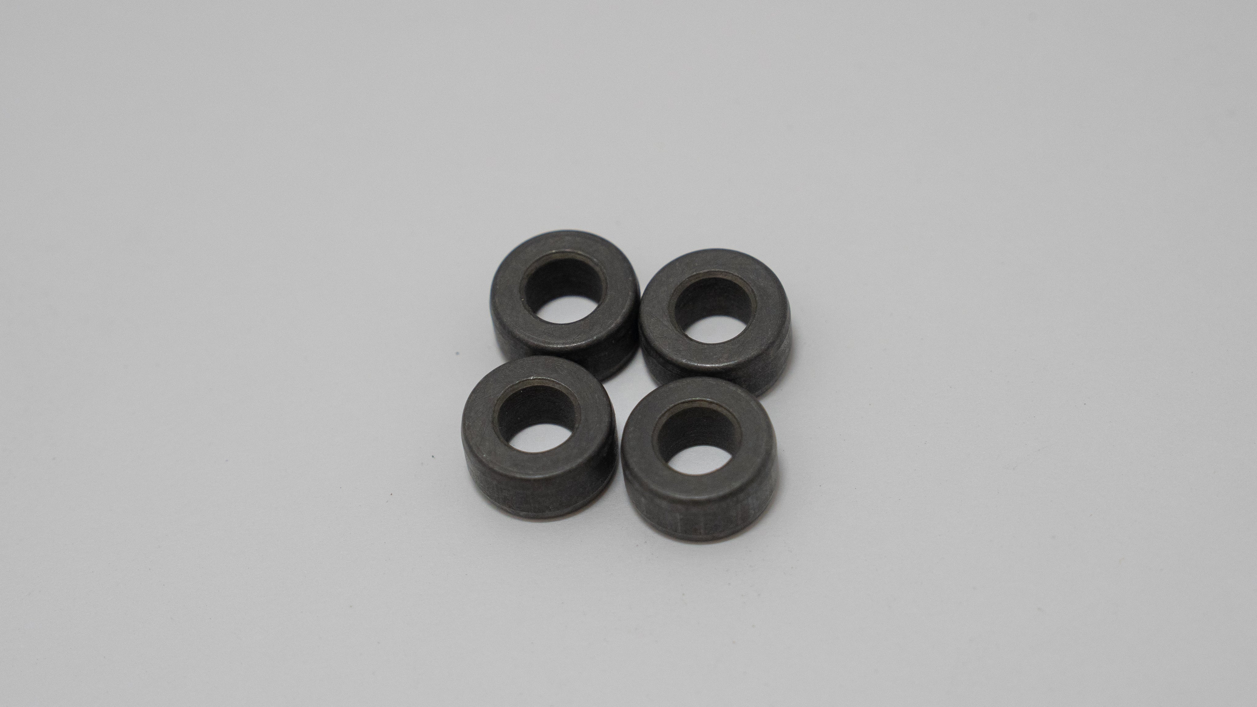 Four black circular automotive spacers  on a gray background.