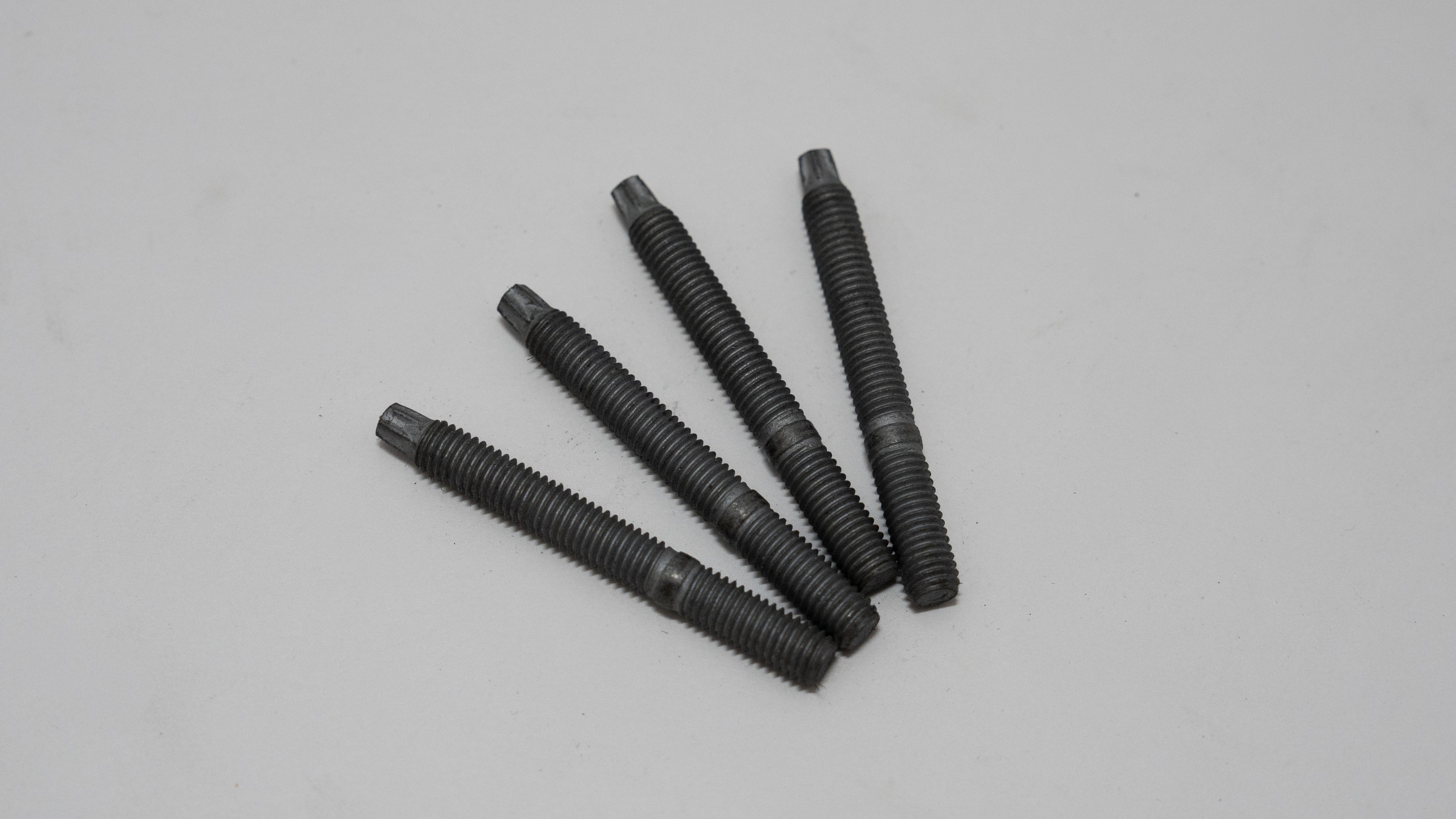 Five black threaded exhaust manifold studs on a gray background