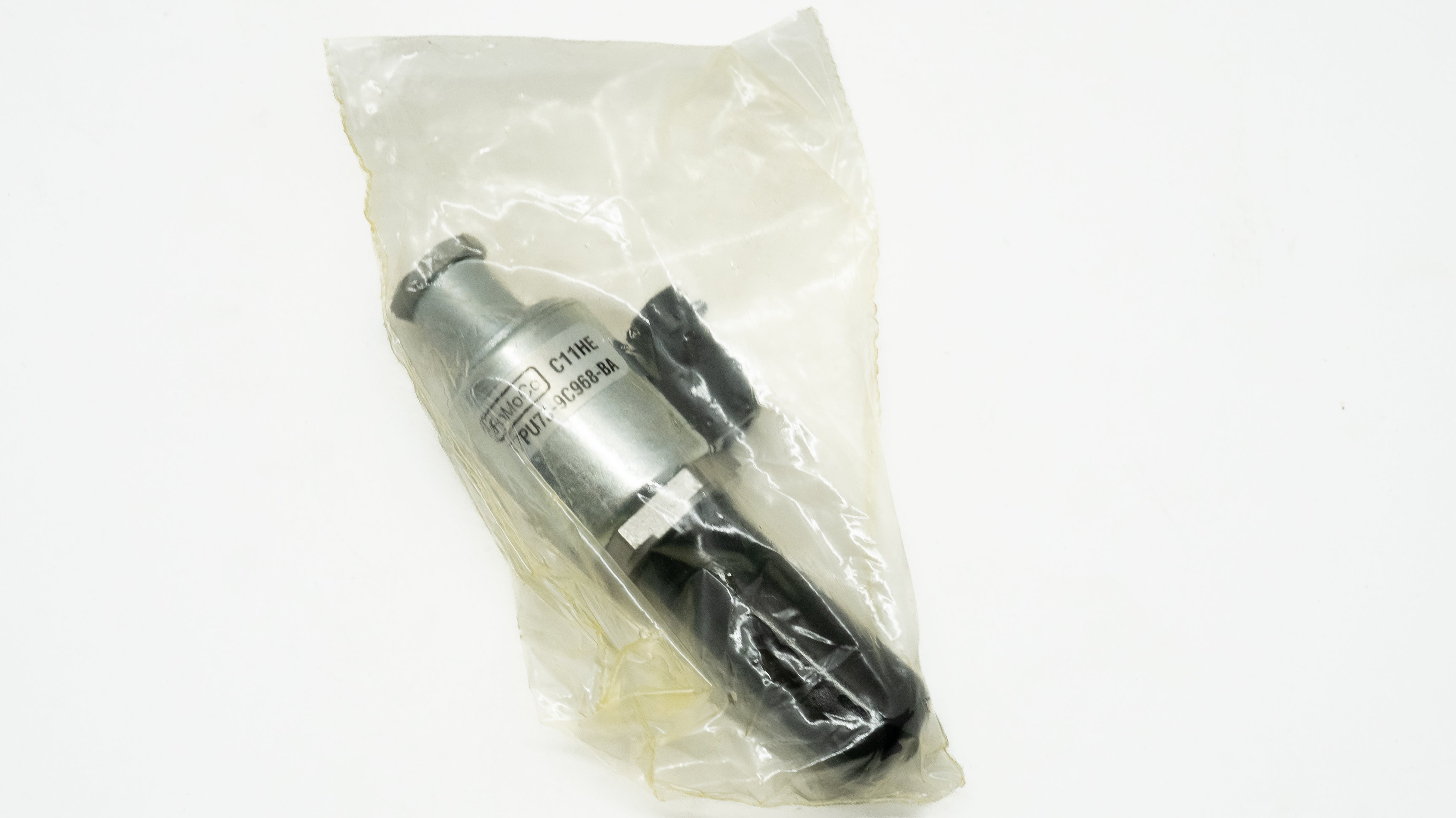 Metallic automotive cylindrical object in a clear plastic bag on a white background