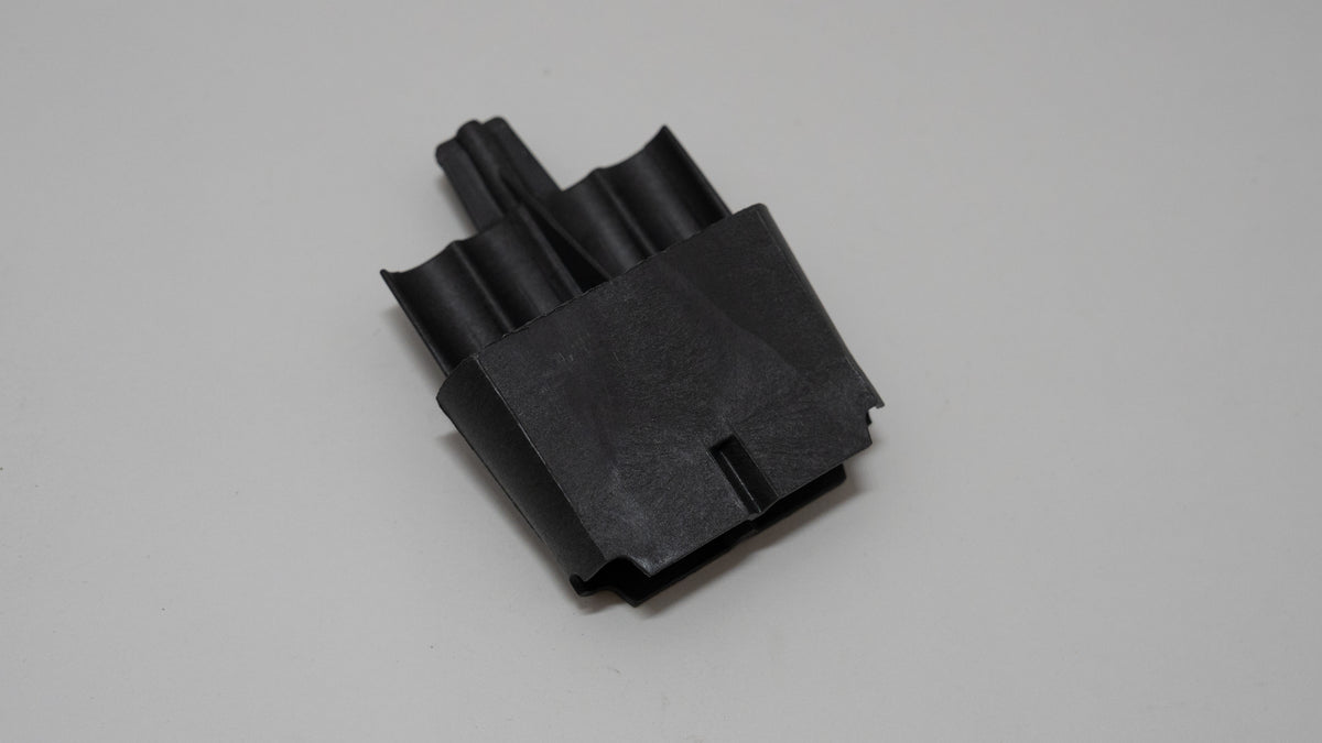 Black automotive plastic component on a gray background