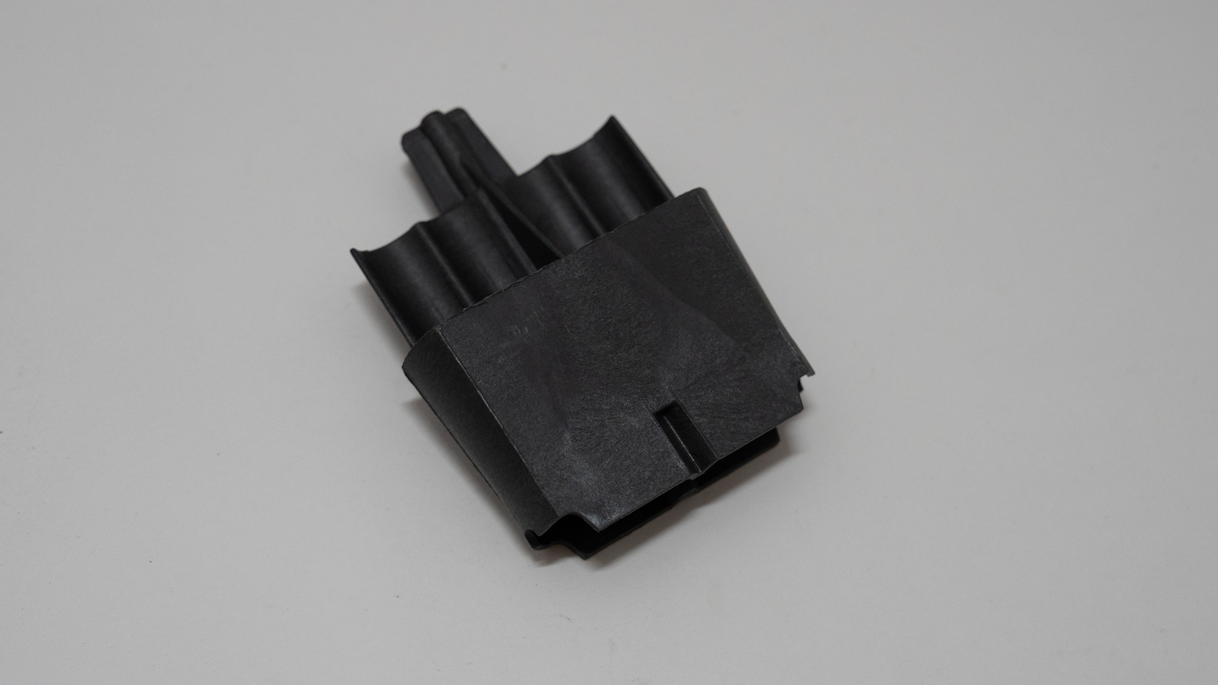 Black automotive plastic component on a gray background