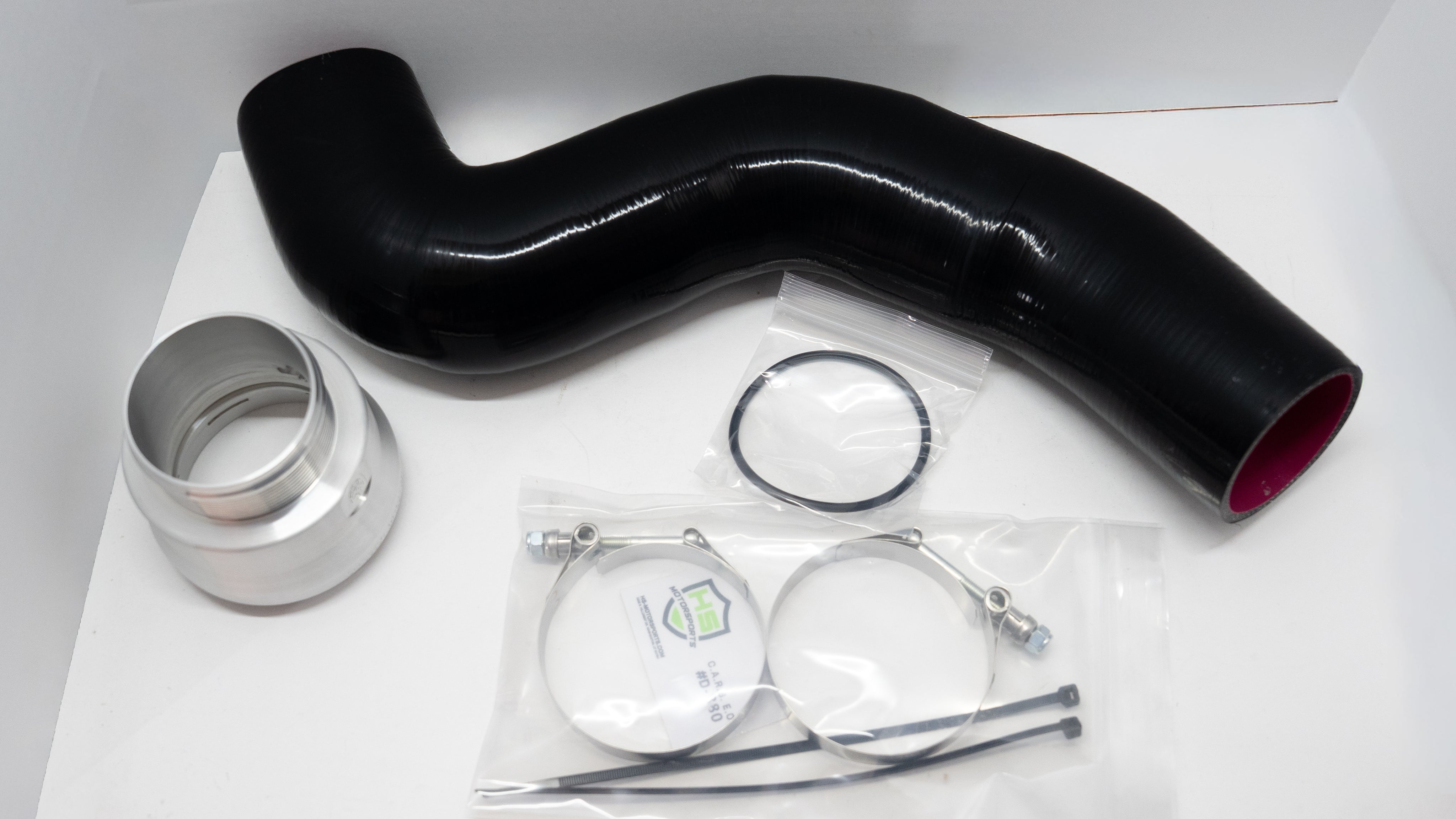 Black silicone automotive pipe with connector and clamps on a white background. 