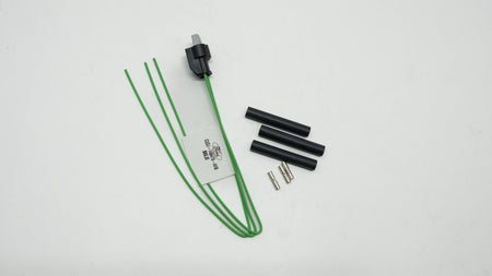 Electrical components including a green cable, black connectors, and a white label on a light gray background.