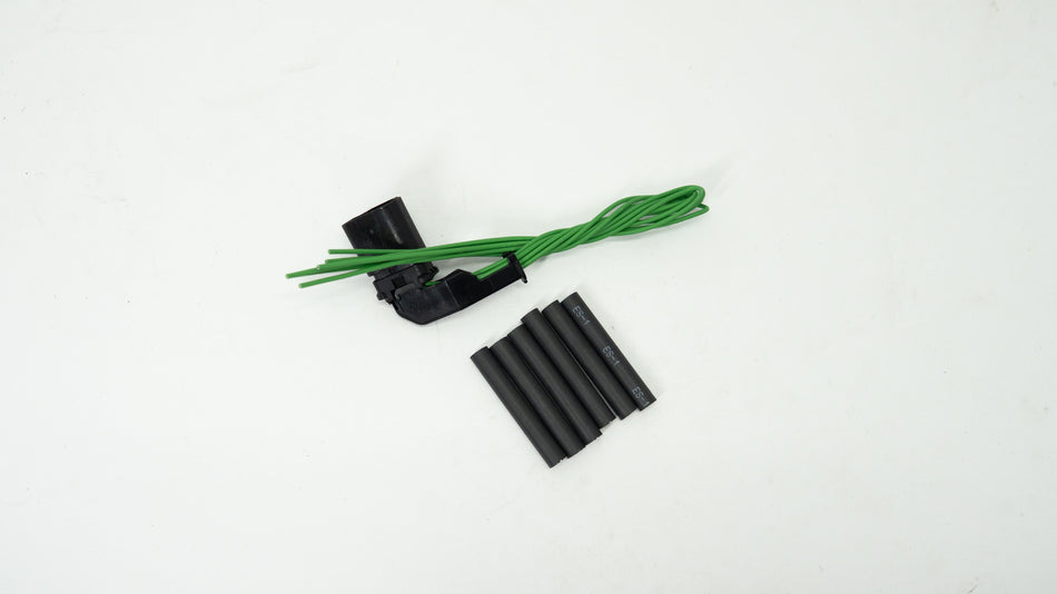 Black and green automotive wiring components on a white background