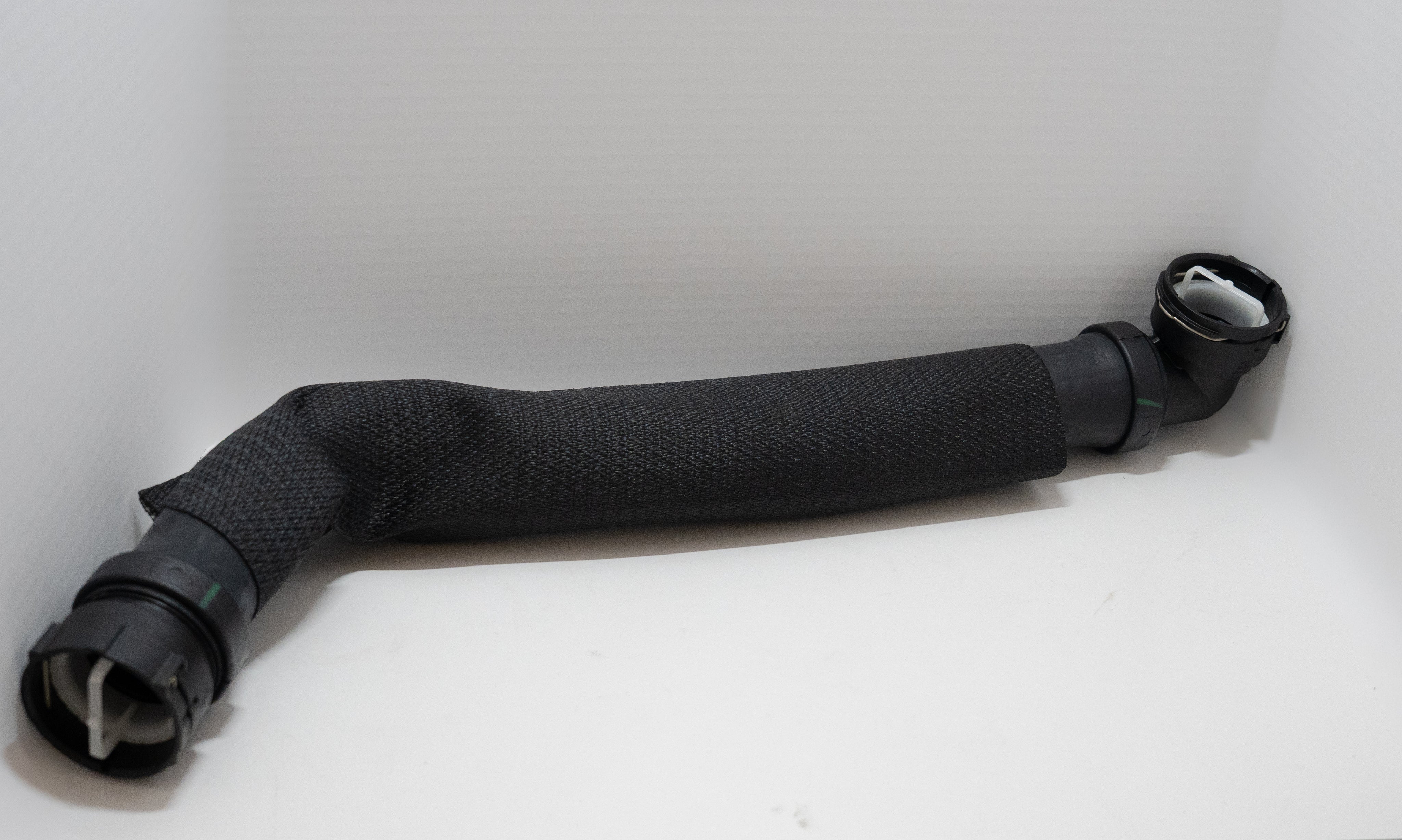 Black rubber automotive hose with couplers on a white background