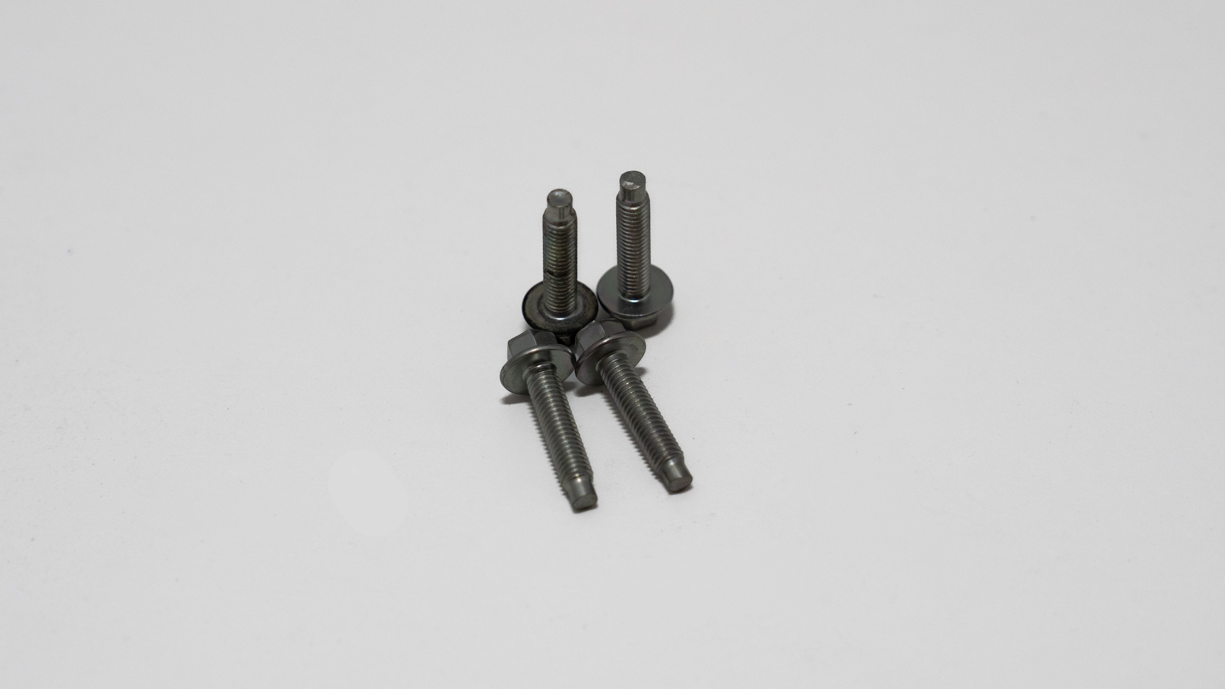 Four automotive tie down bolts, with hex screw head on white background.