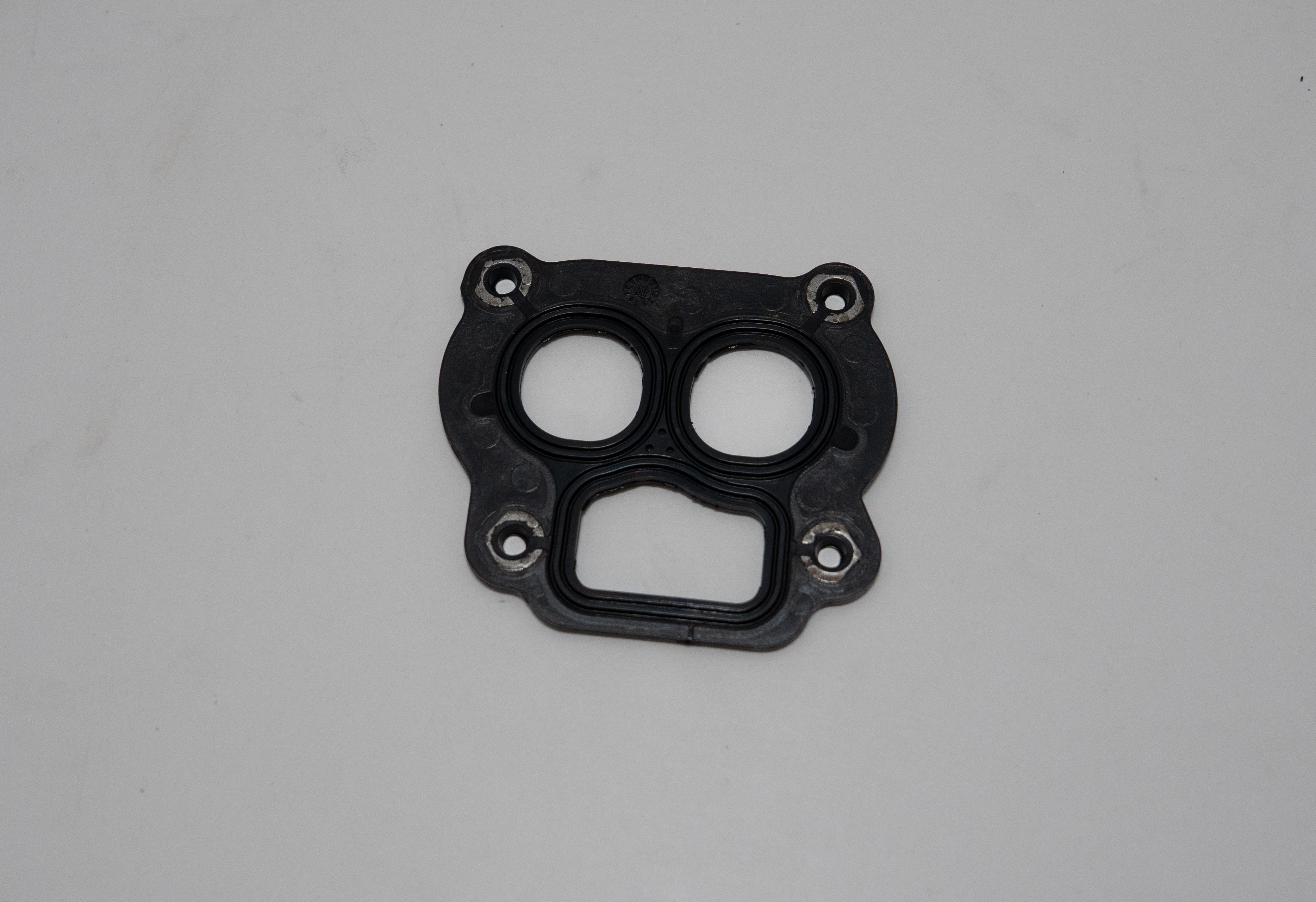 Black automotive gasket on a gray background.
